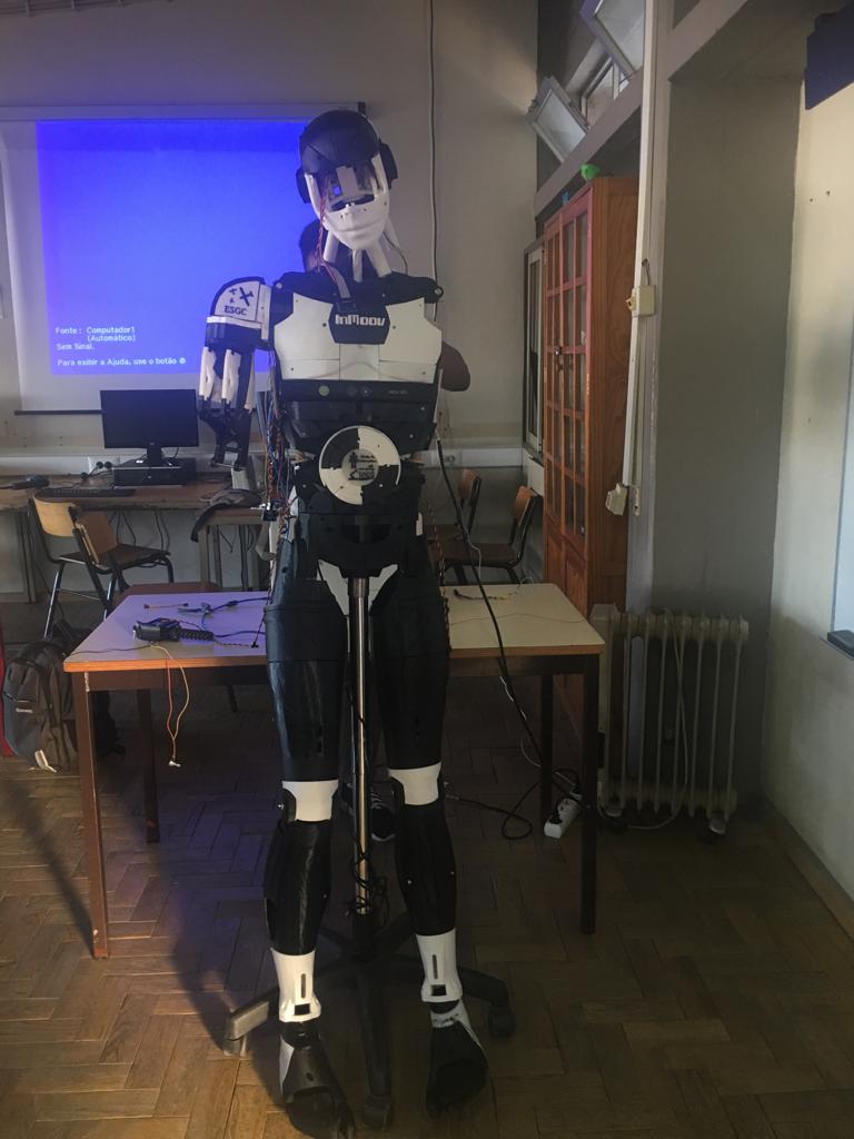 The full-height InMoov robot standing on its support stand in a classroom, legs and torso complete.