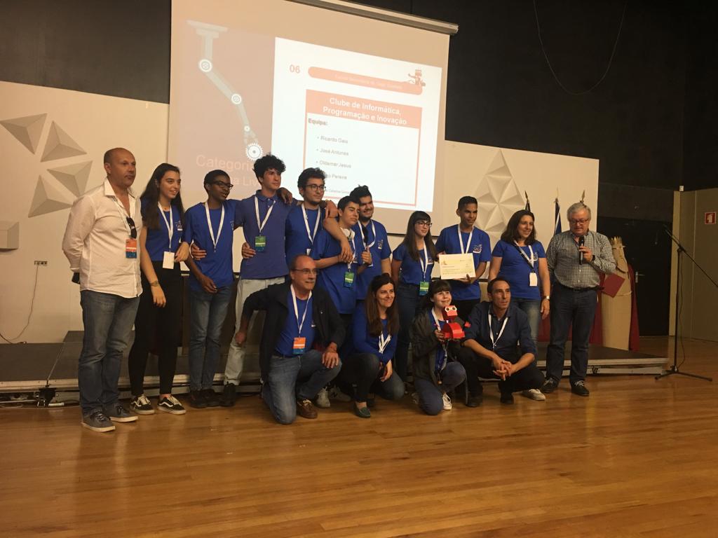 The full club team on stage at the national final holding their award certificate, with the entry slide projected behind them.